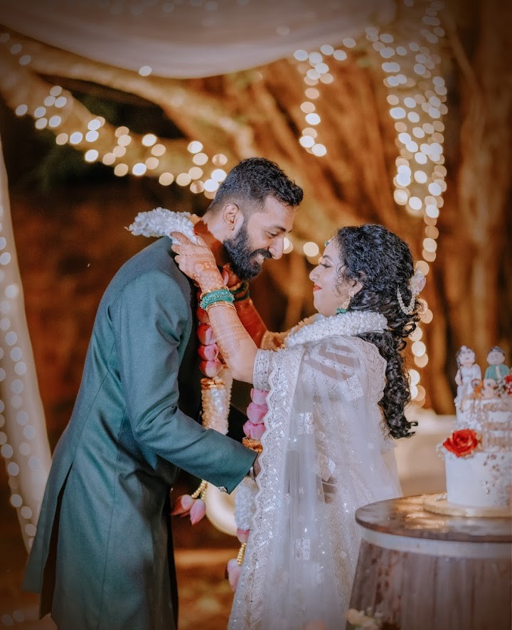 Wedding ceremony portrait by Udayaa Studio — couple sharing a warm moment under fairy-light bokeh